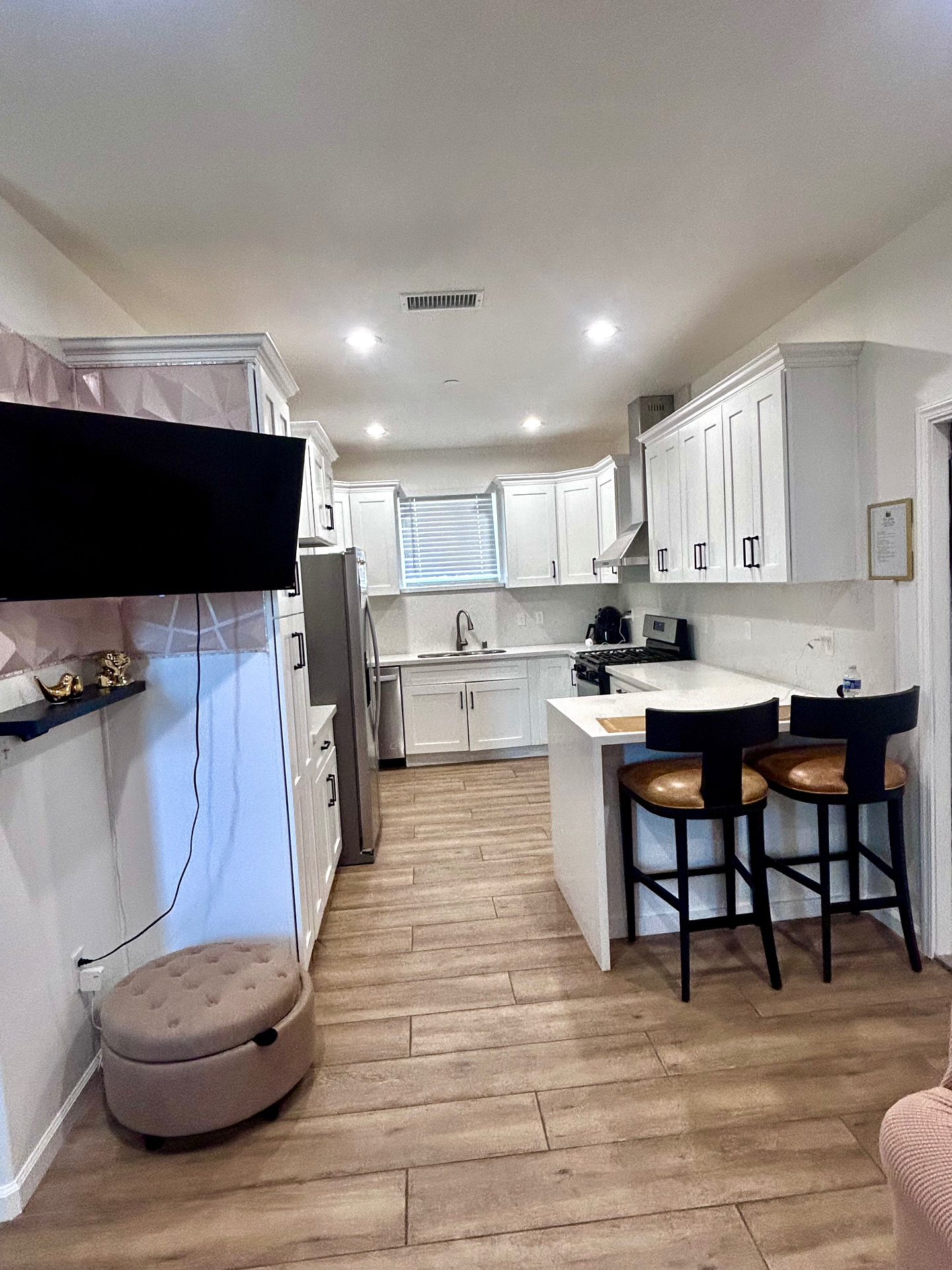 Bright shared kitchen with white cabinetry and dining bar at Our Solace by JW